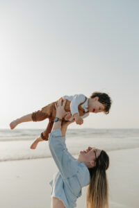 Petit garçon riant dans les bras de son père sur la plage à Vannes