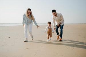 Parents et enfant de 2 ans marchant dans l’eau, séance photo naturelle dans le Morbihan