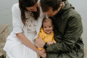 Famille avec bébé partageant un moment tendre sur une plage du Morbihan